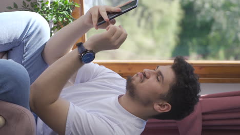 Vertical-video-of-Man-texting-with-happy-expression.
